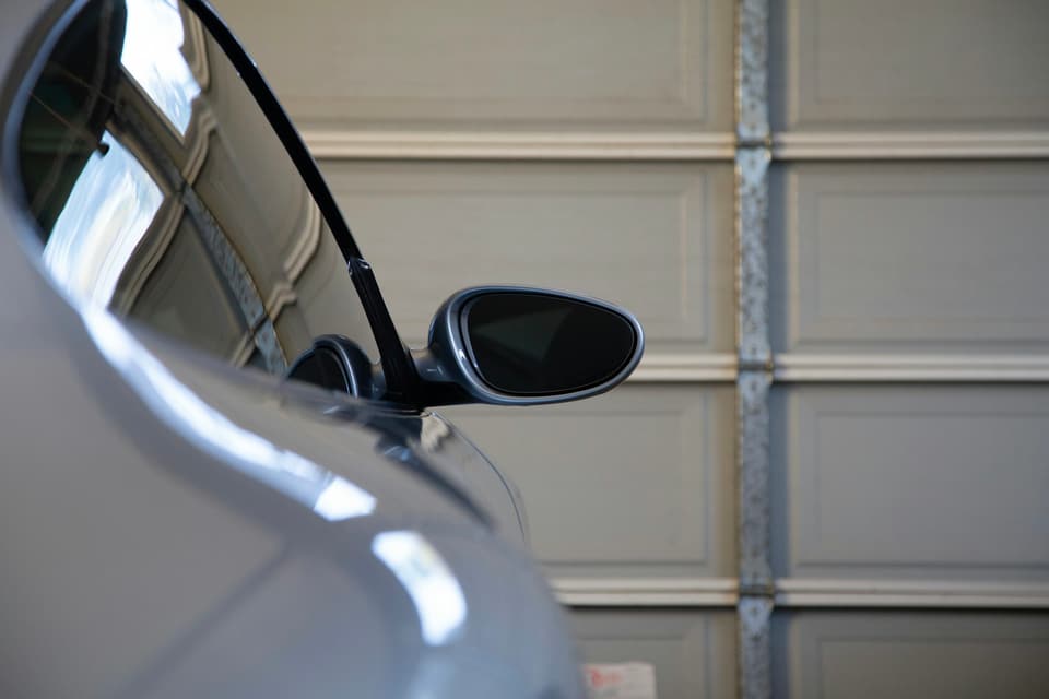 A car parked in front of a closed raised-panel garage door